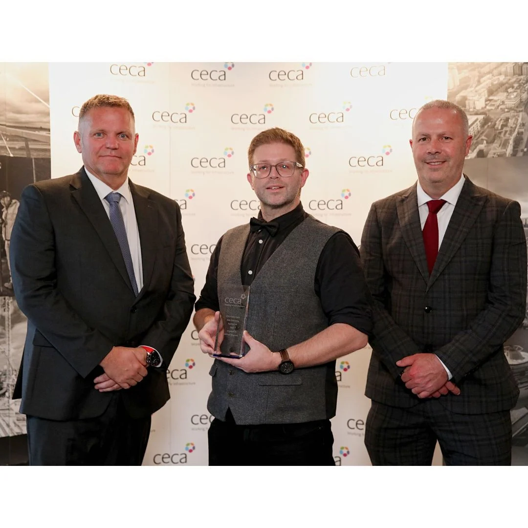 Three attendees at a CECA award presentation, with the central attendee holding a trophy