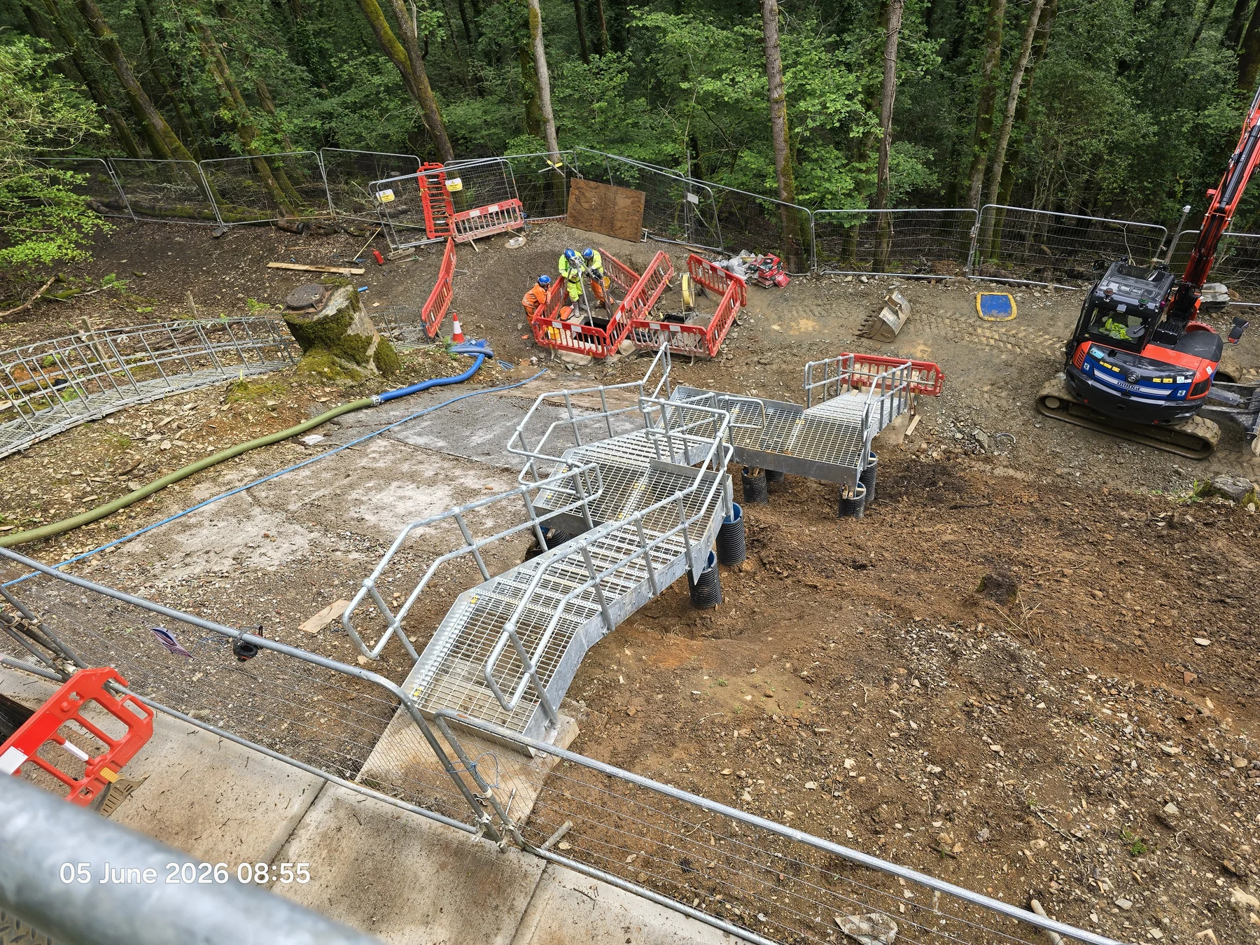 Glenholt Sewage Pumping Station upgrade works with metal access platforms, operatives and an excavator in a wooded site