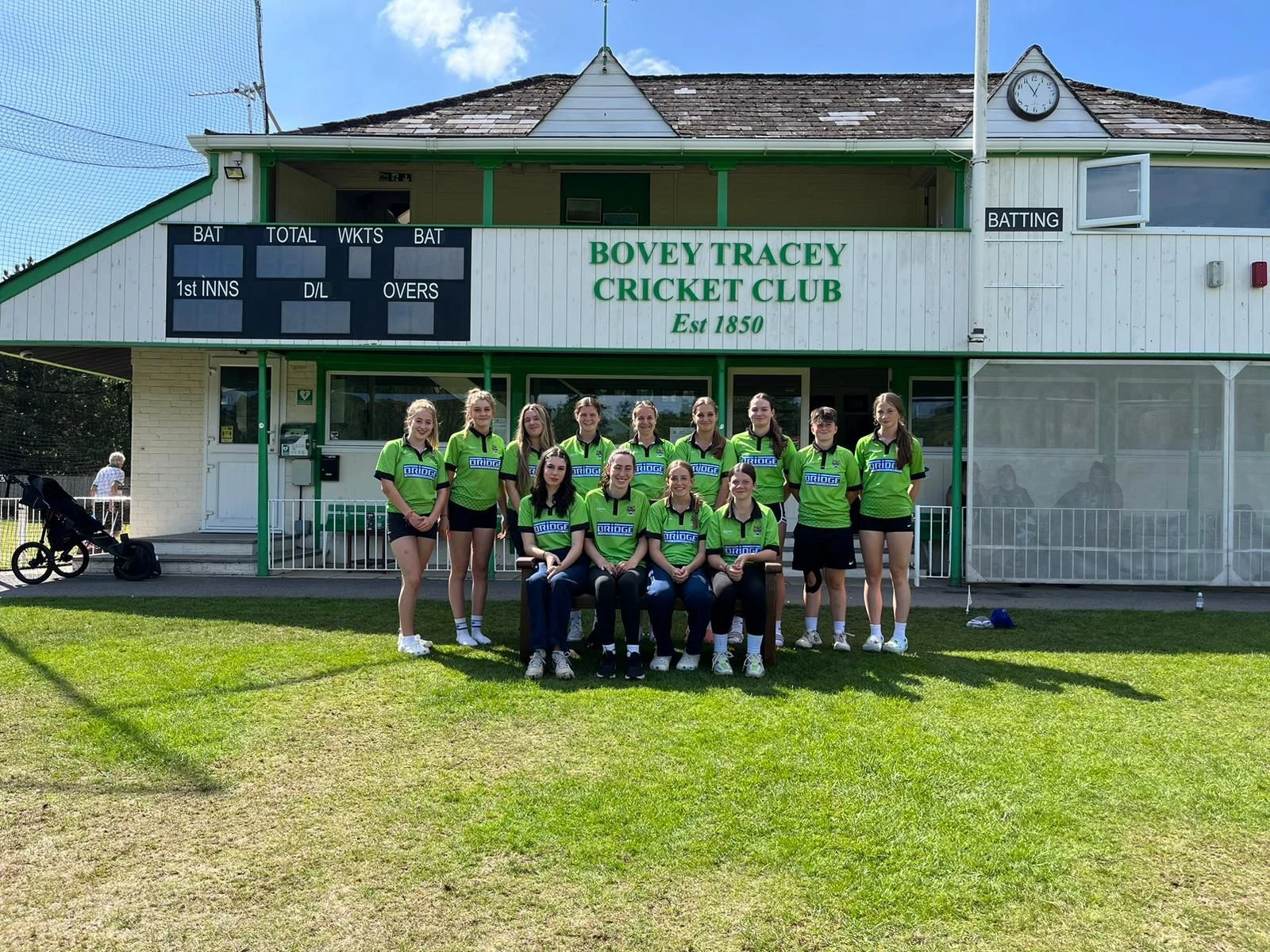 Bovey Tracey Cricket Club team in Bridge-sponsored shirts outside the clubhouse