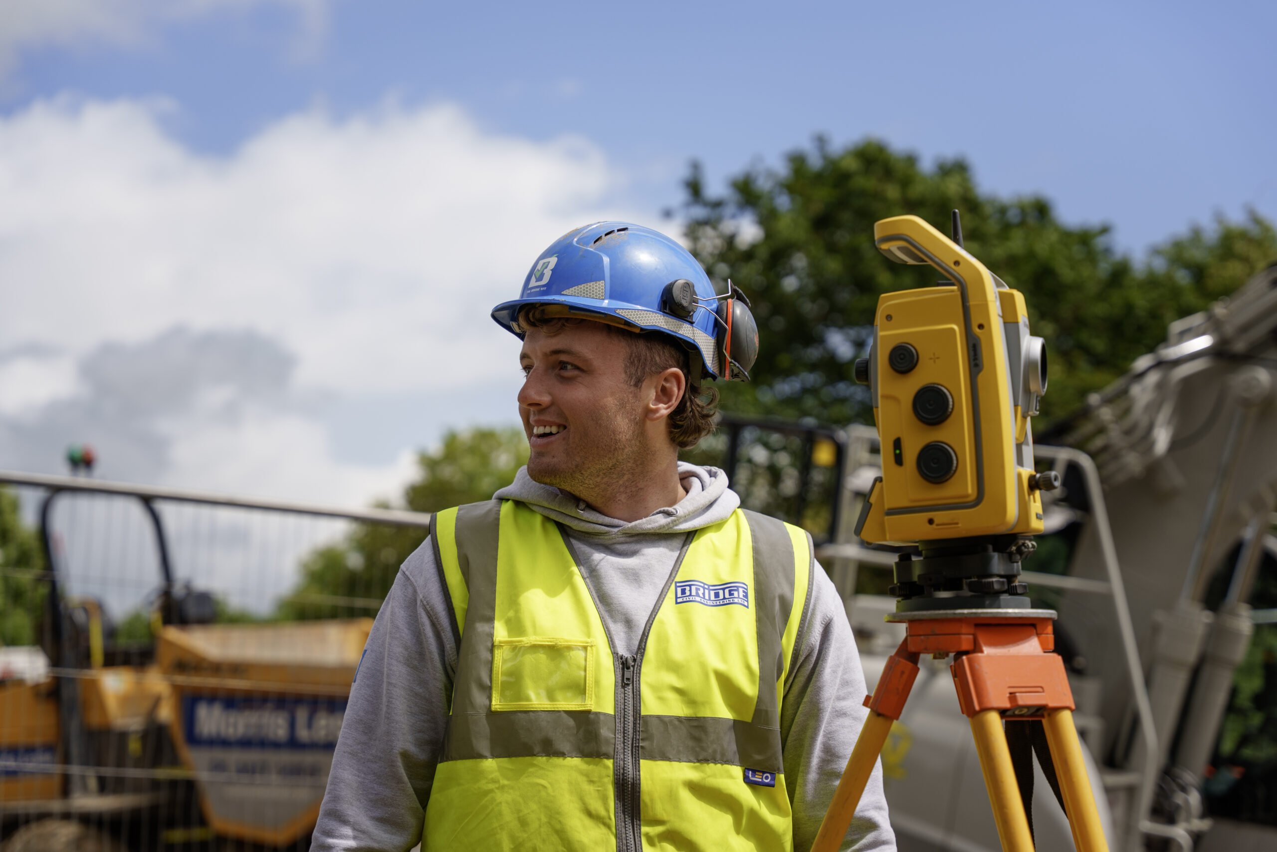 Bridge colleague in safety gear beside surveying equipment
